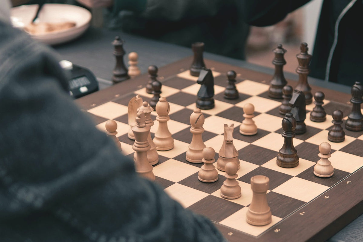 A chess game mid play with a clock beside the board